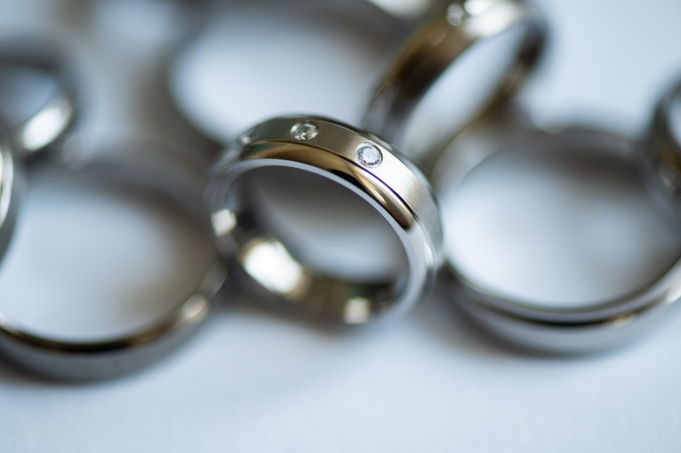 Nahaufnahme eines schlichten Titanrings von ReWi Titan mit zwei eingesetzten Diamanten, polierte und mattierte Oberfläche im Detail, umgeben von weiteren Ringen im Hintergrund