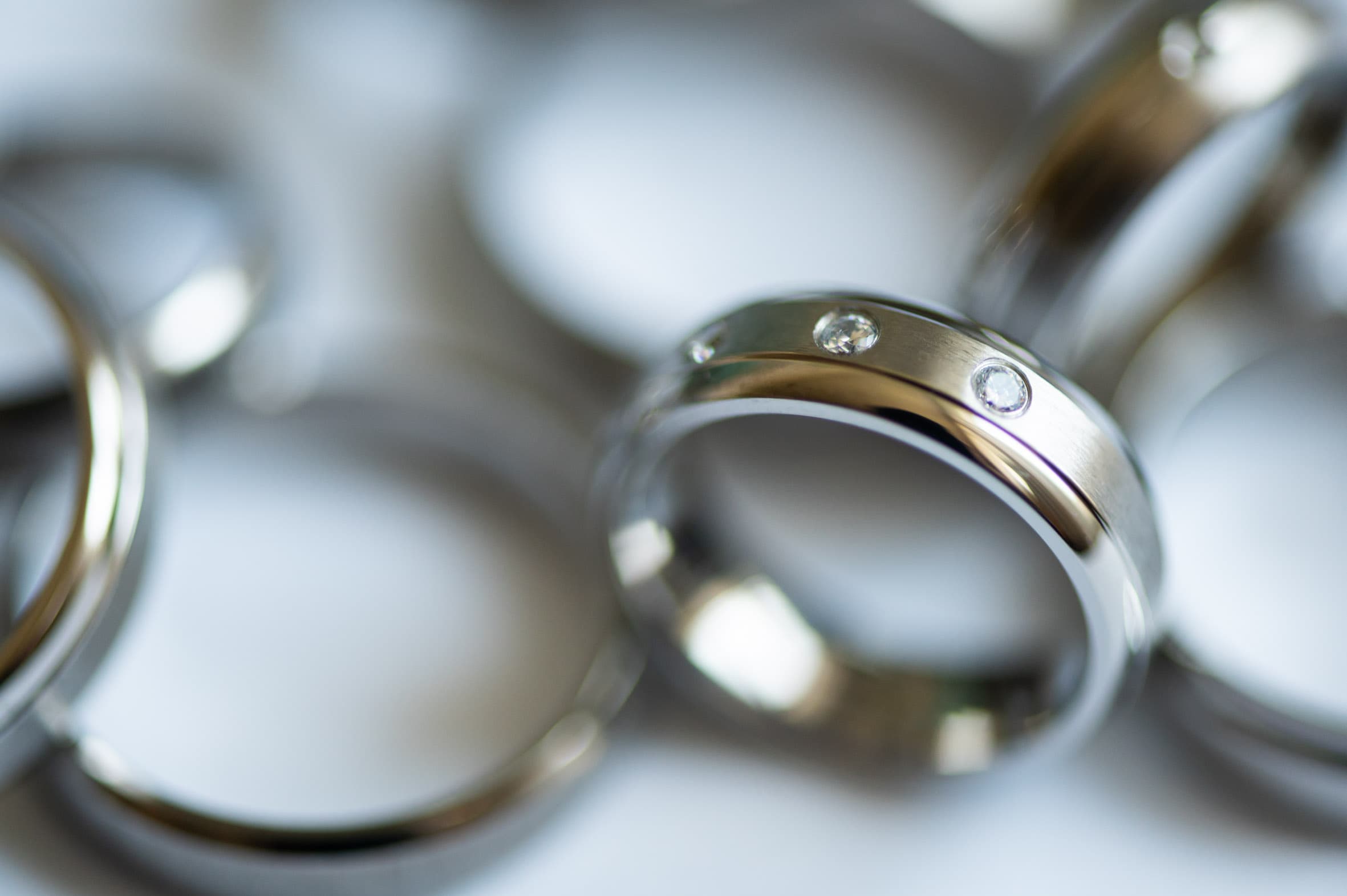 Detailaufnahme eines Titanrings von ReWi Titan mit zwei eingelassenen Diamanten, Kombination aus mattierter und polierter Oberfläche, umgeben von weiteren schlichten Titanringen im Hintergrund
