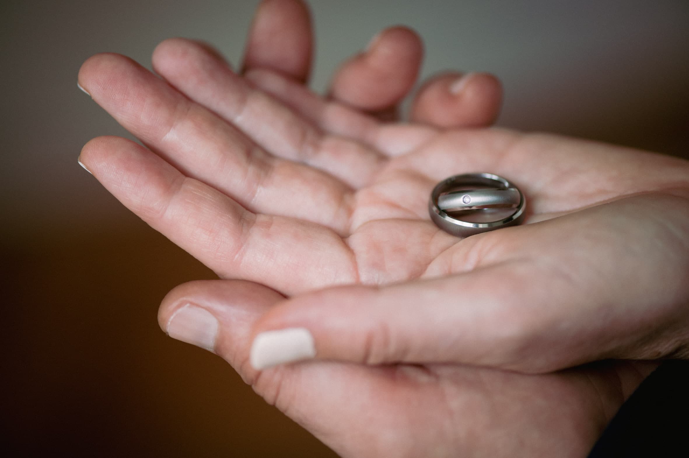 Zwei schlichte Titanringe von ReWi Titan liegen in einer geöffneten Hand, mattierte Oberfläche mit dezent gefasstem Diamanten als Symbol für Partnerschaft und Beständigkeit