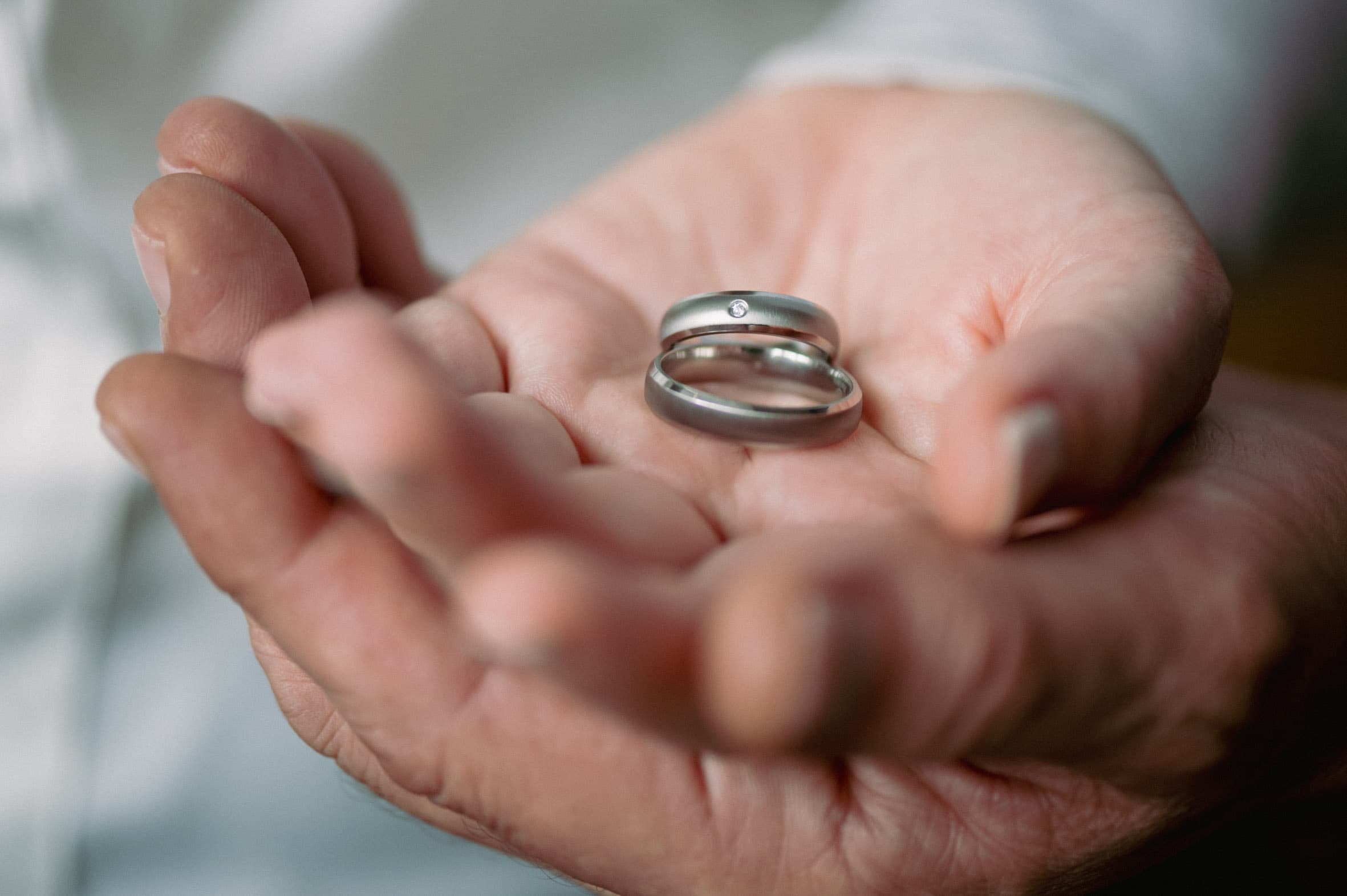 Zwei schlichte Titanringe von ReWi Titan liegen in einer geöffneten Hand, matte Oberfläche mit dezent gefasstem Diamanten als Symbol für Partnerschaft und langfristige Verbundenheit