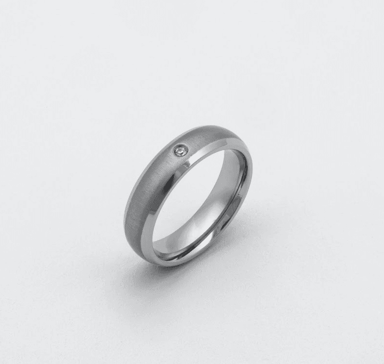 Schlichter Titanring von ReWi Titan mit mattierter Oberfläche und bündig gefasstem Diamanten, polierte Innenkante, freigestellt auf hellem Hintergrund